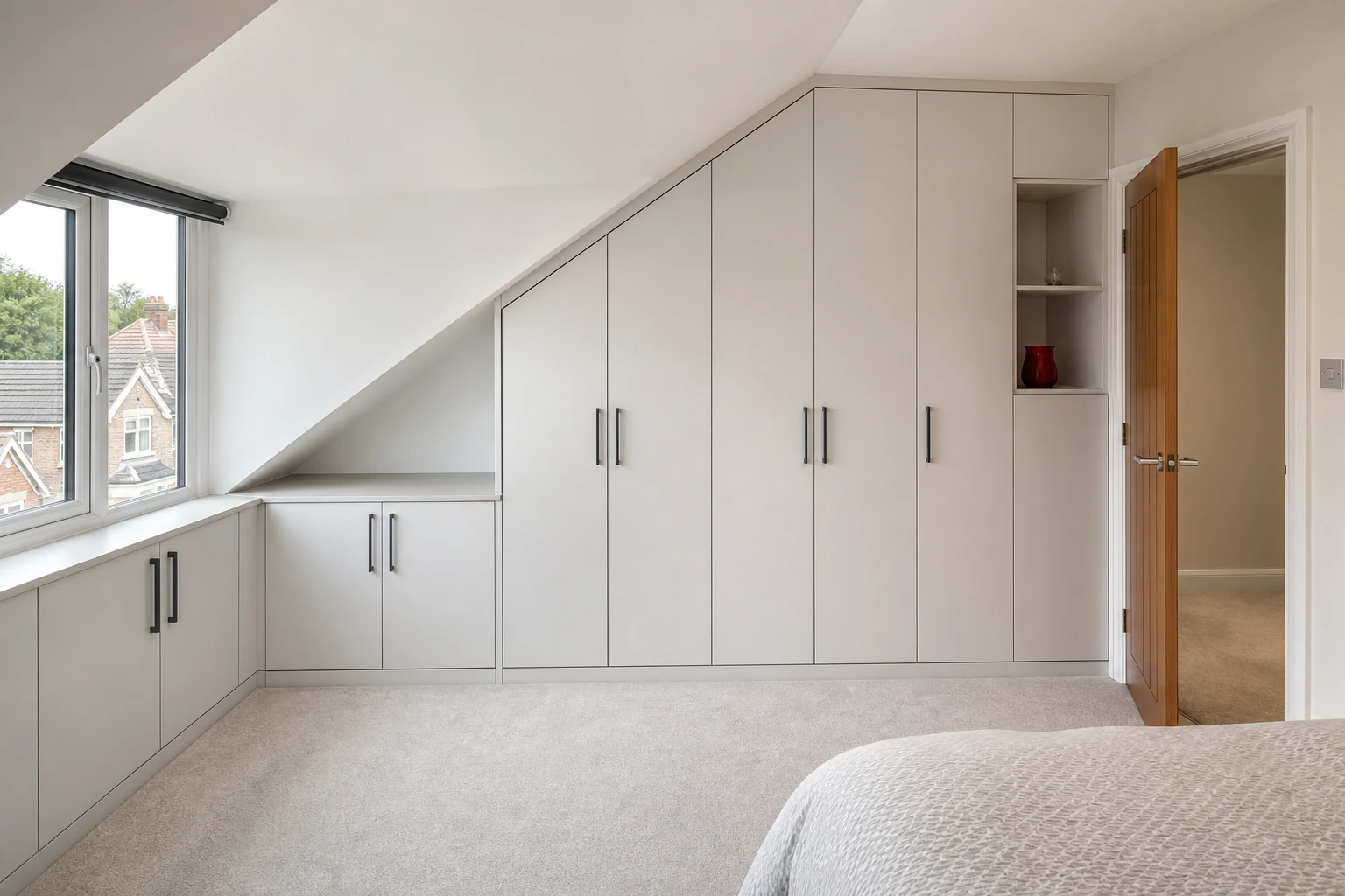 Graduated fitted wardrobes built neatly beneath a sloped bedroom ceiling.