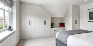 Modern fitted bedroom storage built around a sloped ceiling and alcove.